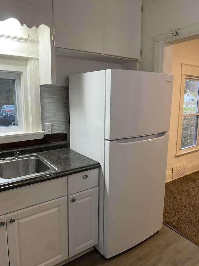 kitchen with white cabinetry, sink, decorative backsplash, hardwood / wood-style flooring, and white fridge