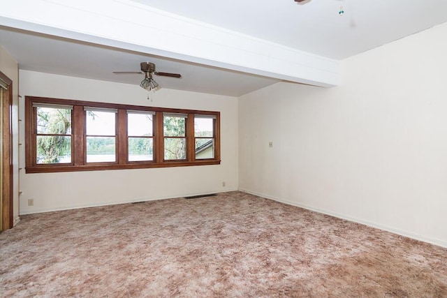 carpeted empty room with beamed ceiling, plenty of natural light, and ceiling fan