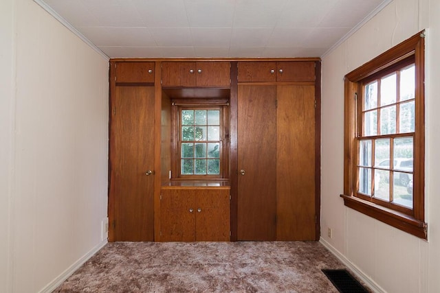 doorway featuring light carpet, ornamental molding, and a healthy amount of sunlight