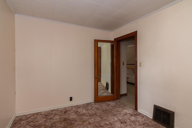 empty room with ornamental molding and light colored carpet