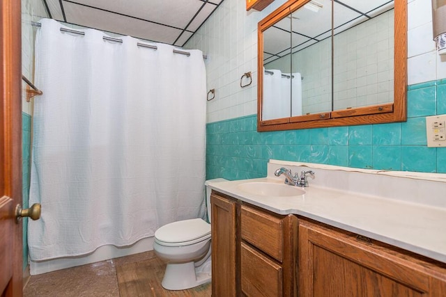 bathroom featuring vanity, tile walls, and toilet