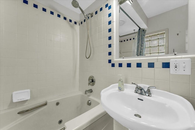 bathroom featuring tiled shower / bath combo, sink, tile walls, and backsplash