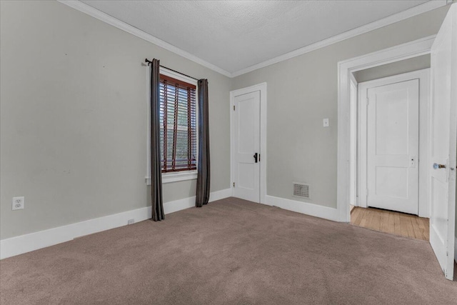 carpeted spare room with crown molding and a textured ceiling