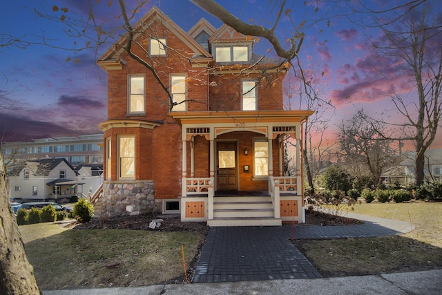 view of front facade with brick siding, a porch, and an attached garage