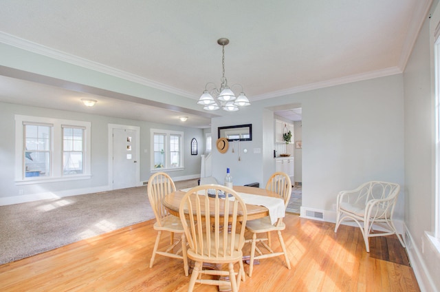 dining space featuring crown molding, a chandelier, and light hardwood / wood-style floors