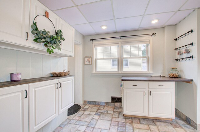 kitchen with a drop ceiling and white cabinets