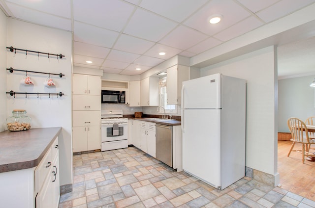 kitchen with white cabinetry, white appliances, sink, and decorative backsplash