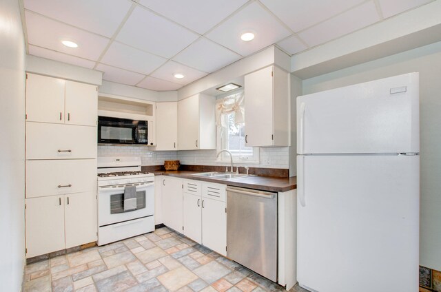 kitchen featuring sink, tasteful backsplash, white cabinets, white appliances, and a drop ceiling