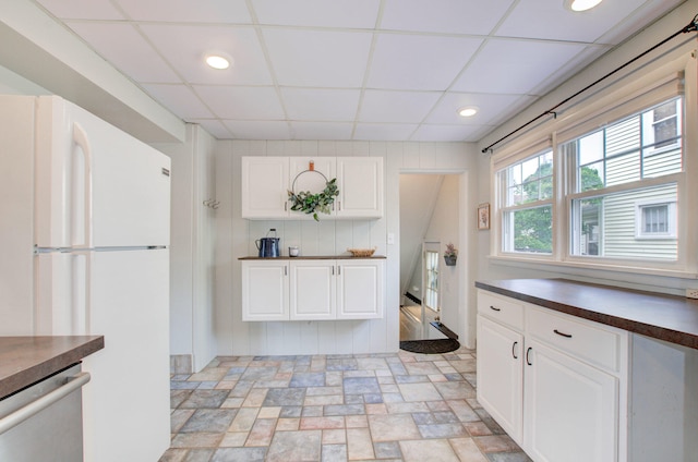 kitchen with dishwasher, white fridge, a paneled ceiling, and white cabinets