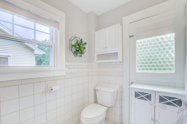 bathroom with tile walls and toilet