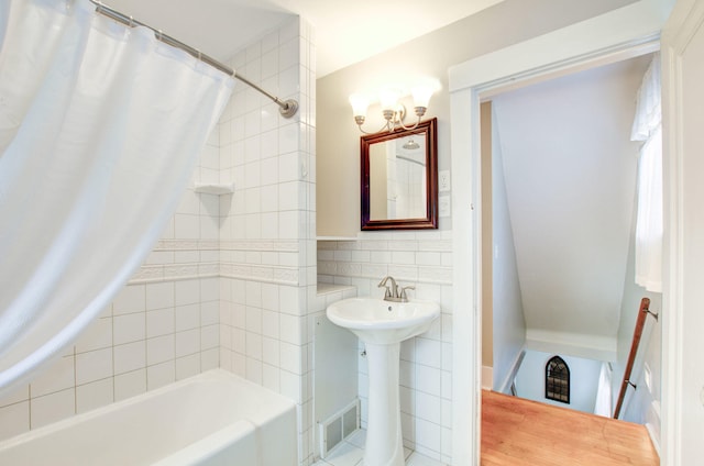 bathroom featuring shower / bath combination with curtain, sink, and tile walls