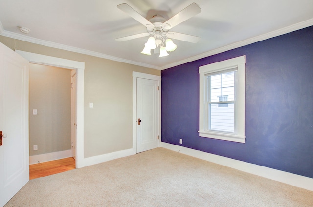 empty room with ornamental molding, light colored carpet, and ceiling fan