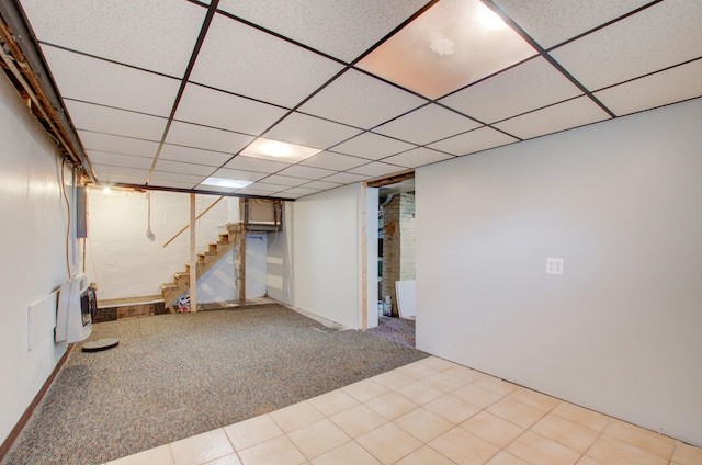 basement featuring light carpet and a paneled ceiling