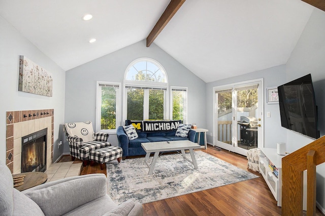 living room featuring a fireplace, plenty of natural light, vaulted ceiling with beams, and light wood-type flooring