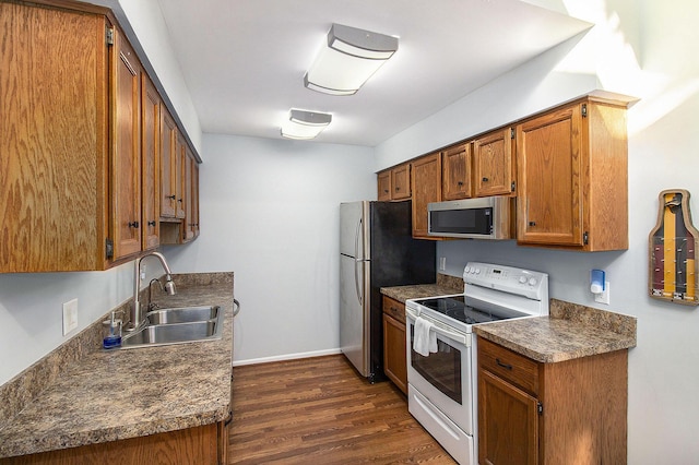 kitchen with appliances with stainless steel finishes, dark hardwood / wood-style floors, and sink