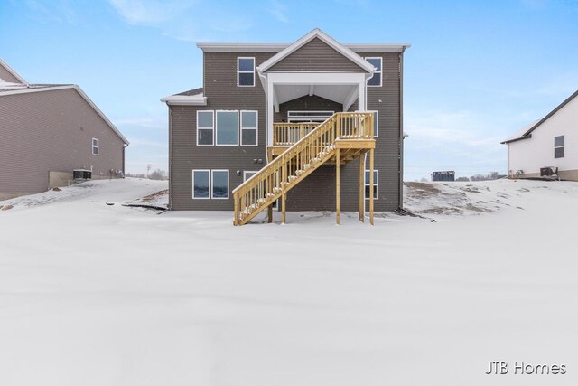 snow covered property featuring stairs and central AC