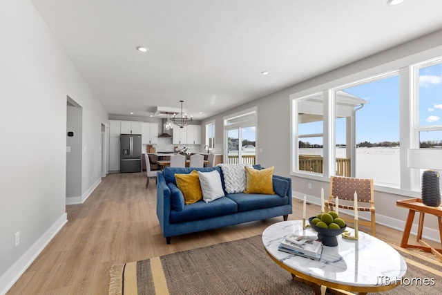 living area with an inviting chandelier, light wood-style flooring, baseboards, and recessed lighting