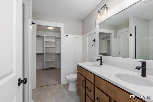 bathroom with a walk in closet, a sink, toilet, and double vanity