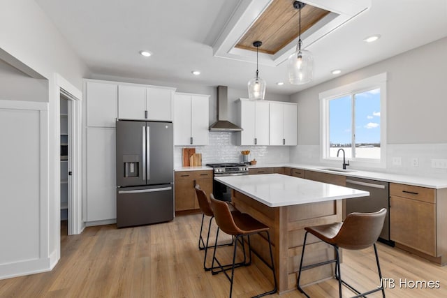 kitchen featuring wall chimney exhaust hood, white cabinetry, stainless steel appliances, and light countertops