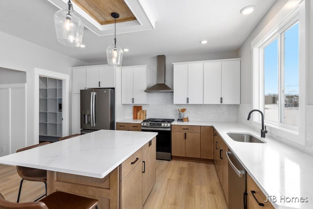 kitchen with stainless steel appliances, a center island, white cabinets, and wall chimney range hood