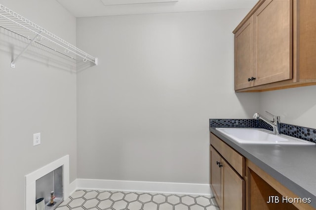 laundry area with hookup for a washing machine, a sink, cabinet space, and baseboards