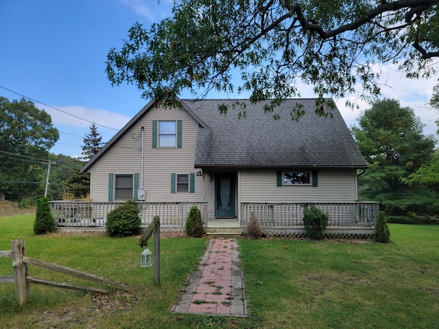 view of front of property with roof with shingles, a wooden deck, and a front lawn