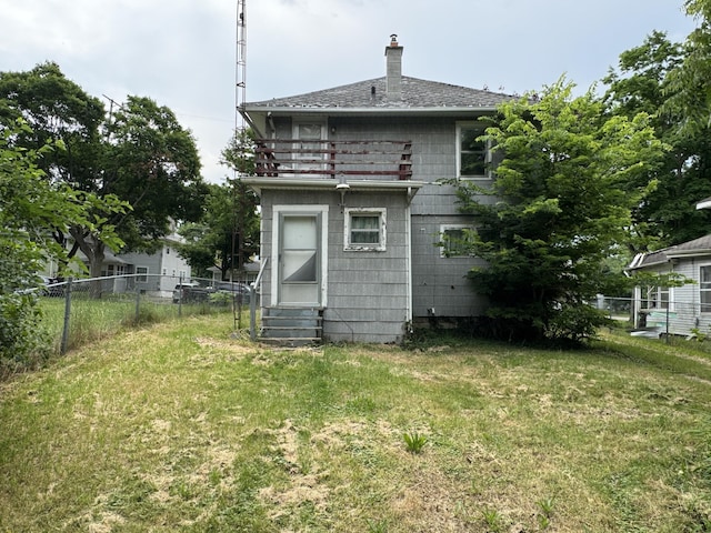 rear view of house featuring a balcony and a lawn