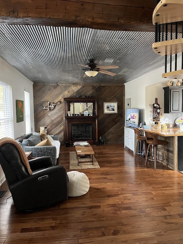 living room with a fireplace, dark hardwood / wood-style floors, ceiling fan, and wood walls