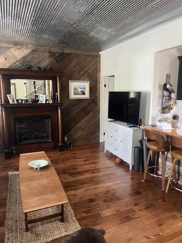 living room with crown molding, dark hardwood / wood-style floors, and wooden walls