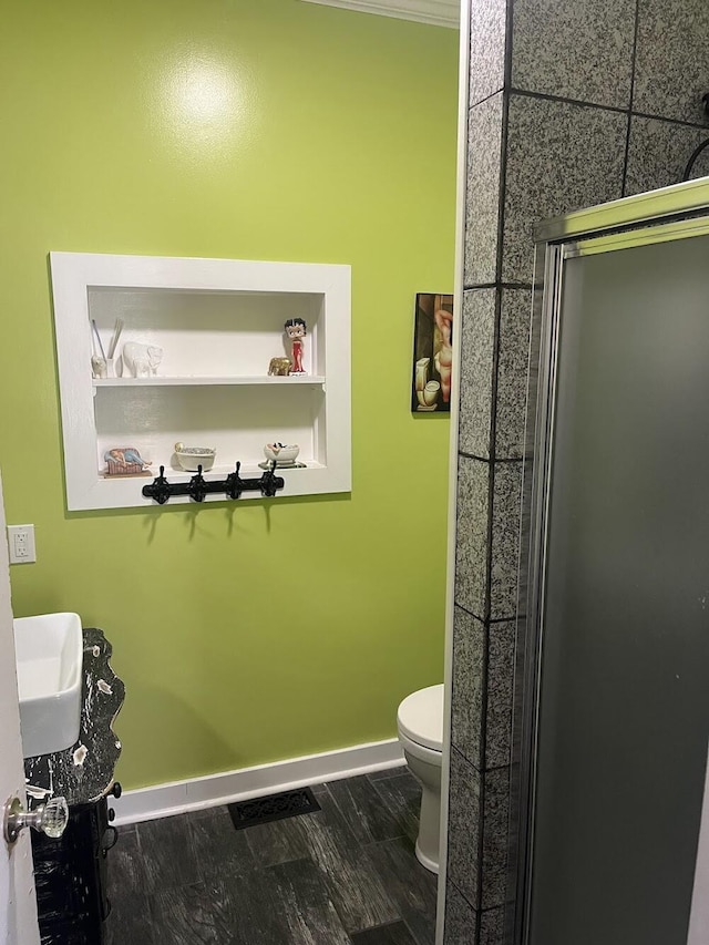 bathroom featuring hardwood / wood-style flooring, an enclosed shower, and toilet