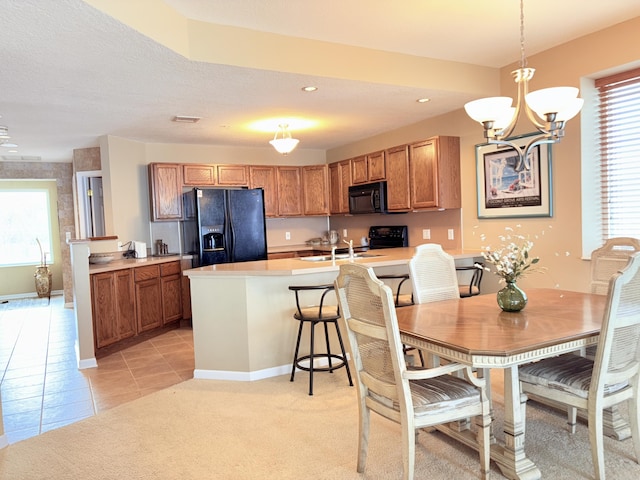 kitchen with a peninsula, black appliances, brown cabinetry, and light countertops