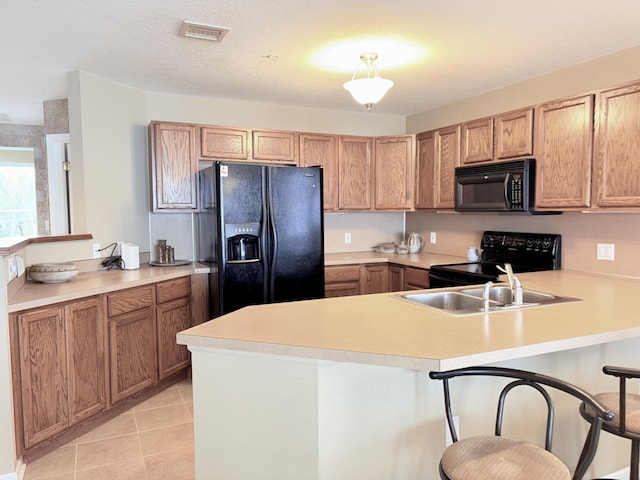 kitchen featuring light countertops, a sink, a peninsula, and black appliances