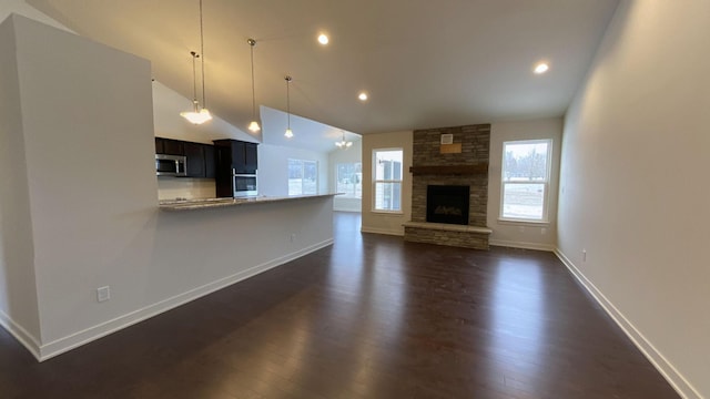 unfurnished living room with a stone fireplace, high vaulted ceiling, and dark hardwood / wood-style floors