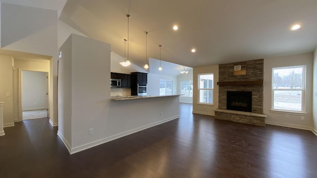 unfurnished living room featuring a stone fireplace, high vaulted ceiling, and dark hardwood / wood-style floors