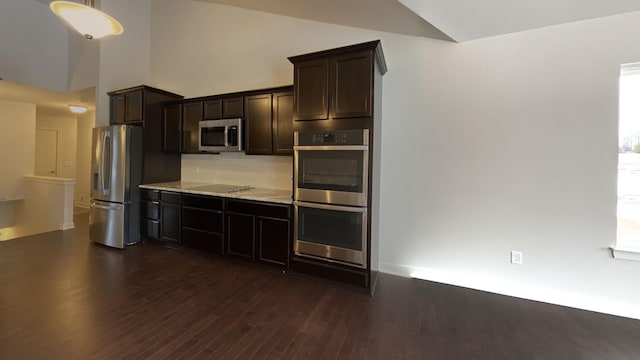 kitchen with light stone counters, dark brown cabinetry, stainless steel appliances, and dark hardwood / wood-style floors