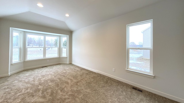 carpeted spare room featuring vaulted ceiling