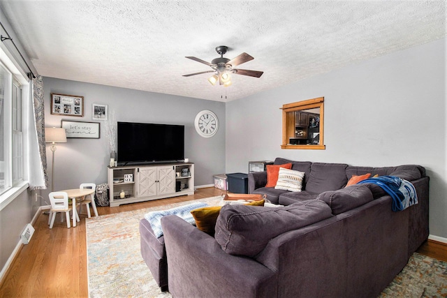 living room featuring hardwood / wood-style flooring, ceiling fan, and a textured ceiling