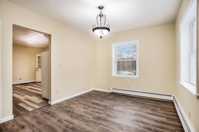 spare room with dark hardwood / wood-style flooring, a baseboard radiator, and a healthy amount of sunlight