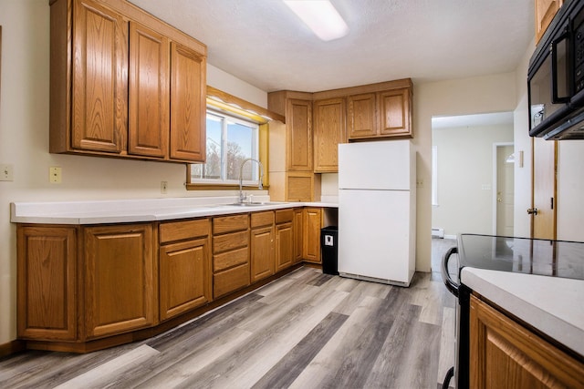 kitchen with electric stove, sink, light wood-type flooring, and white refrigerator