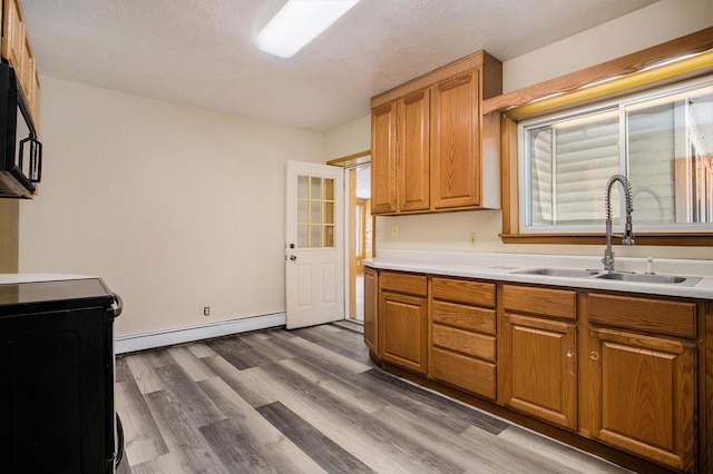 kitchen with dark wood-type flooring, a baseboard radiator, and sink