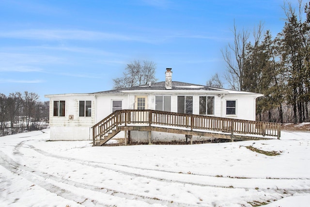 snow covered back of property with a deck