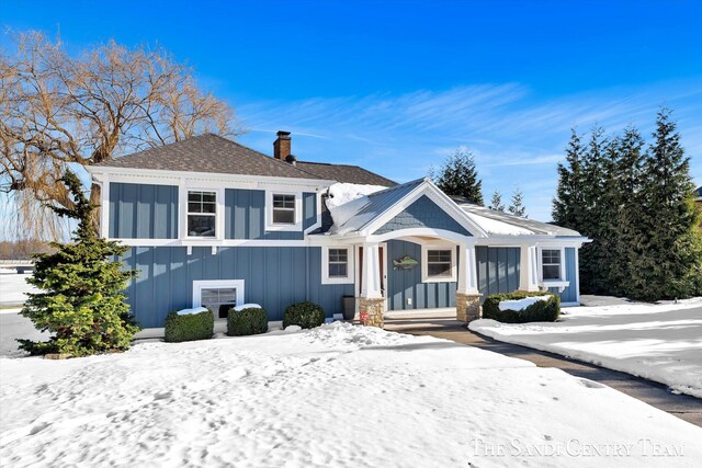 view of front of house featuring a chimney, board and batten siding, and roof with shingles