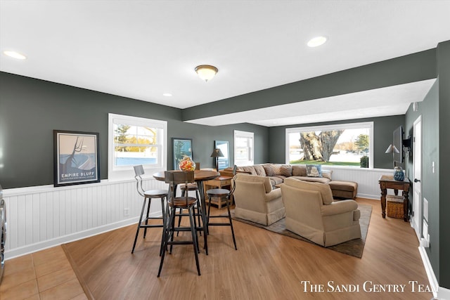 dining area with wainscoting, wood finished floors, and a healthy amount of sunlight