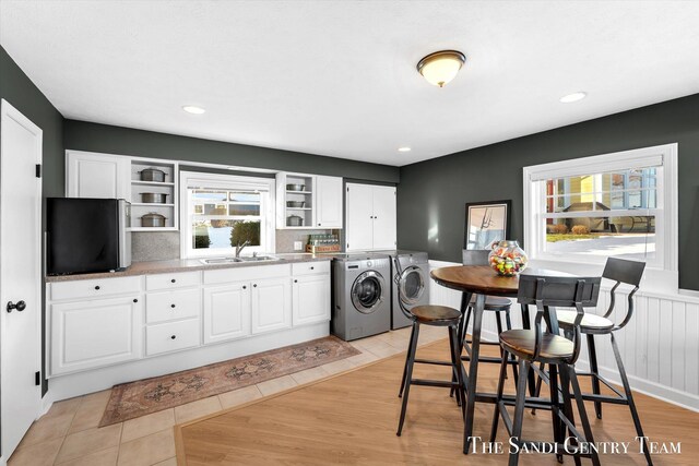 kitchen with white cabinets, a sink, open shelves, and separate washer and dryer