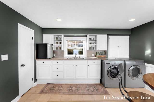 laundry room with light tile patterned floors, independent washer and dryer, a sink, and cabinet space