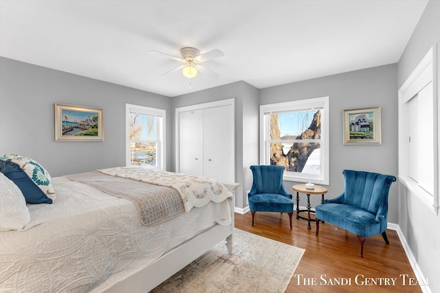 bedroom with a closet, wood finished floors, a ceiling fan, and baseboards