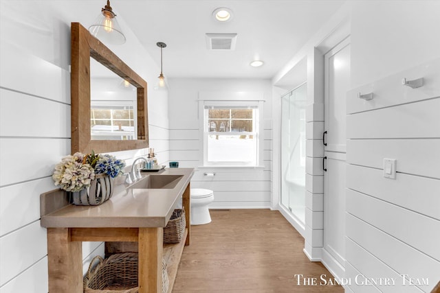 bathroom with toilet, visible vents, a wealth of natural light, and wood finished floors