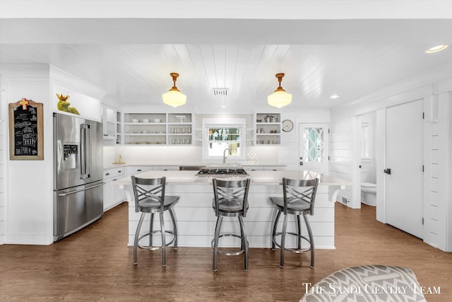 kitchen with open shelves, light countertops, appliances with stainless steel finishes, white cabinets, and a kitchen bar