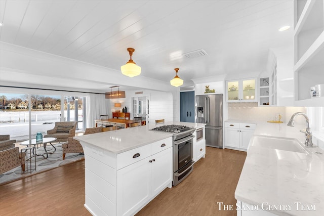 kitchen featuring appliances with stainless steel finishes, open floor plan, a sink, and light wood-style flooring