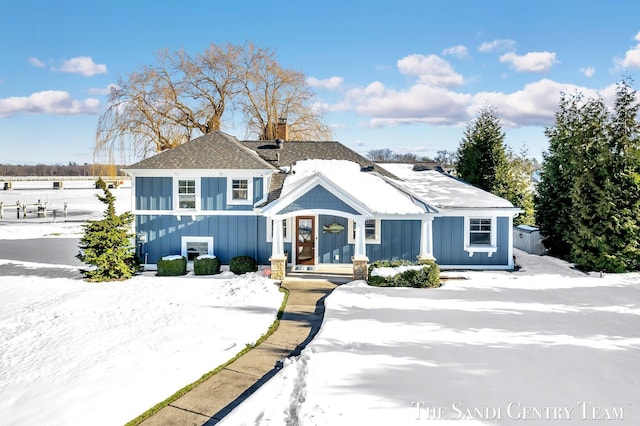 view of front of home with board and batten siding, roof with shingles, and a chimney